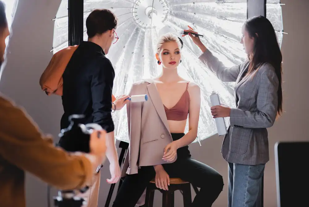 une modèle se fait retoucher le maquillage par une makeup artists lors d'un shooting